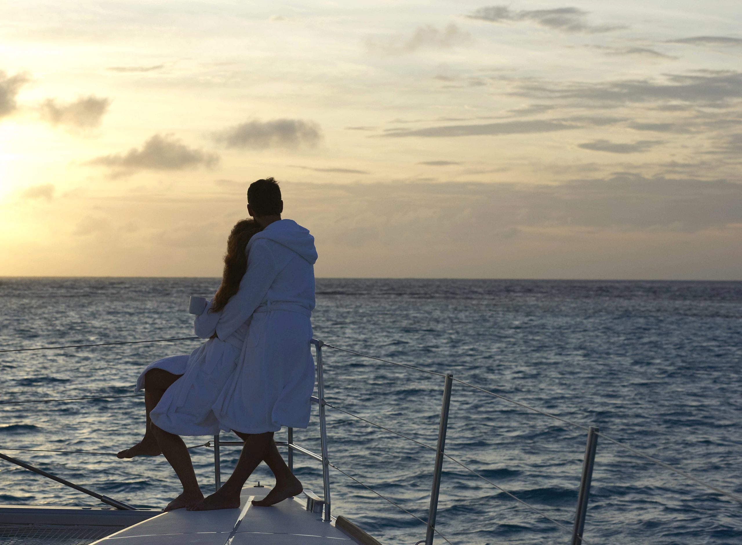 Katamaran segling par i solnedgång