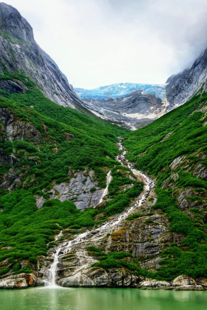 Vattenfall i Alaska längs gröna berg
