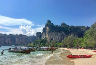 Sandstrand med båtar i Thailand