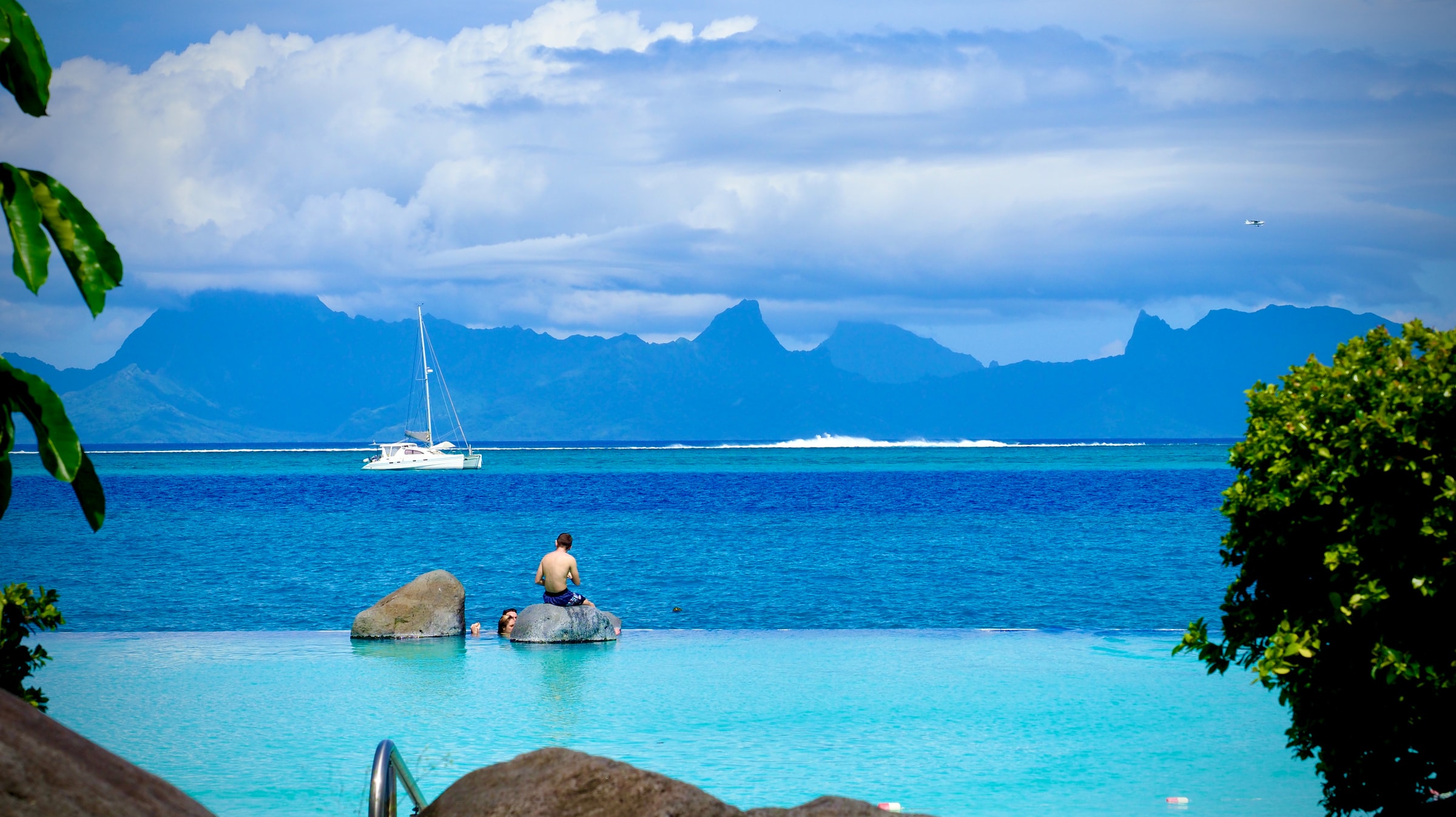 man som sitter på en sten i tahitis blå hav