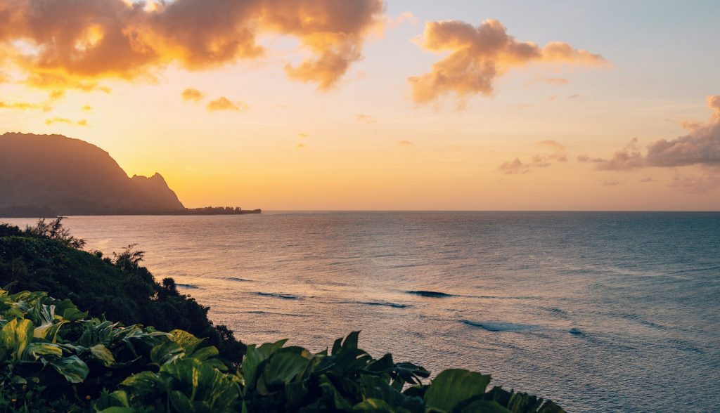 Solnegång på Kauai ön i Hawaii med rosa och gula färger över Stilla Havet